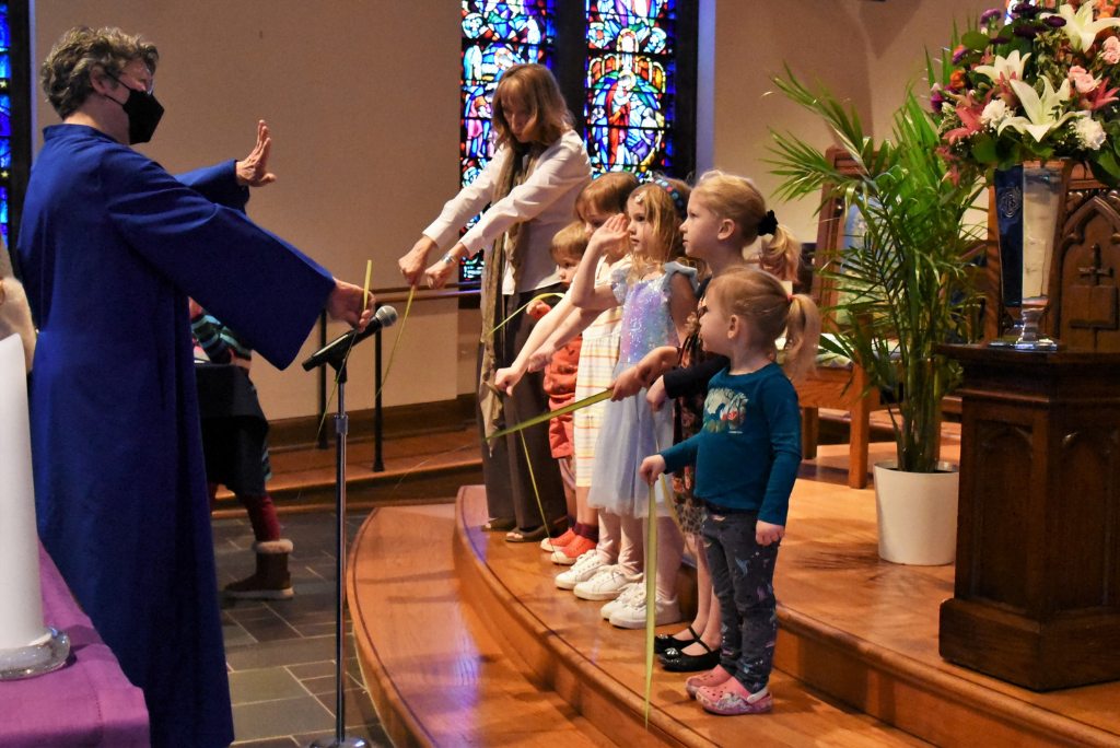 Four little girls and one little boy holding psalm and standing on the steps of the altar at Towson Presbyterian church being instructed by older woman.